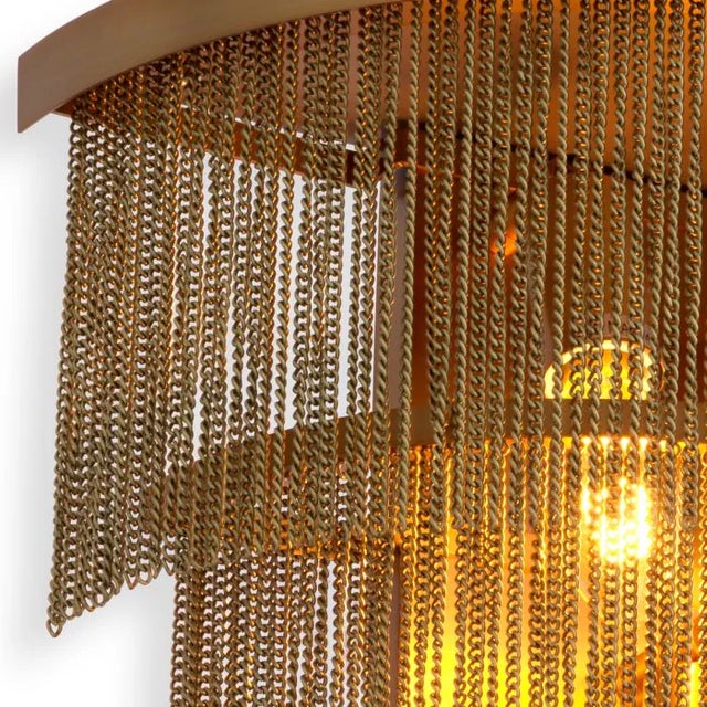 Three tiers of thin chains remind one of fringe flapper dresses from the 1920s. Provided with an antique brass finish,...