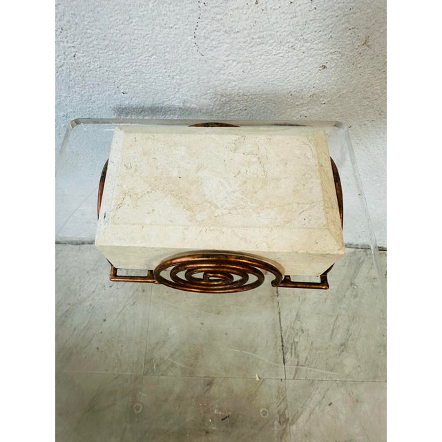 A decorative stone keepsake or jewelry box with an Art Deco–inspired design. The rectangular cream-toned box sits within a...