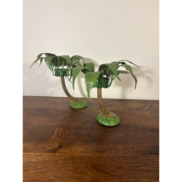 A mirrored pair of 1980s palm tree candle holders by Petite Choses. Sculptural curved trunks with candle cups nestled in...