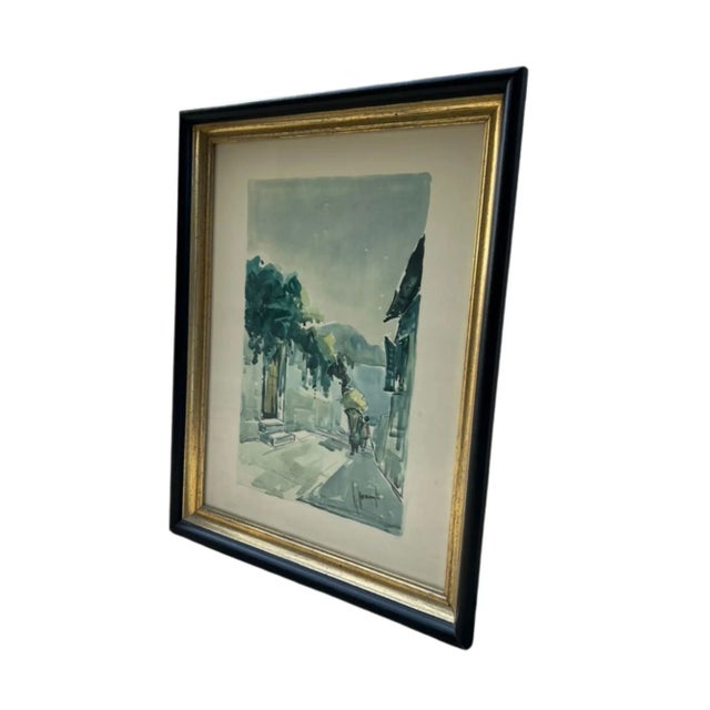 This artwork is a delicate watercolor street scene, painted in soft washes of blue-green, gray, and muted earthy tones....