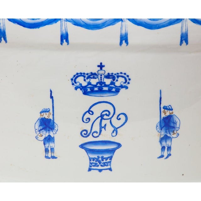 With applied handles to the sides, painted in blue monochrome with band of swags under the rim, over crown, shield motifs...
