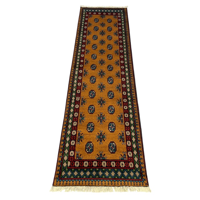 This terracotta-brown runner features two rows of repeating geometric gul motifs, accented with teal blue, cream, green,...