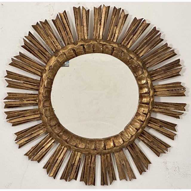 A beautiful French gilt sunburst (or starburst) mirror with gilded rays arranged around a mirror plate glass center....