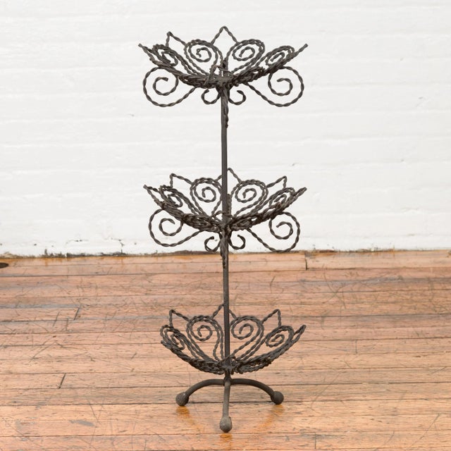 A vintage bronze three-tiered stand from the mid-20th century, with scrolled motifs. Created with the traditional...
