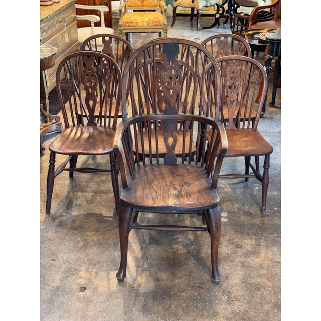 A set of seven English Windsor chairs, each with a hooped back filled with turned spindles about a pierced splat, the side...