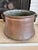 A substantial 19th-century hand-hammered copper cauldron featuring hand-forged iron swing handles and beautiful timeworn...