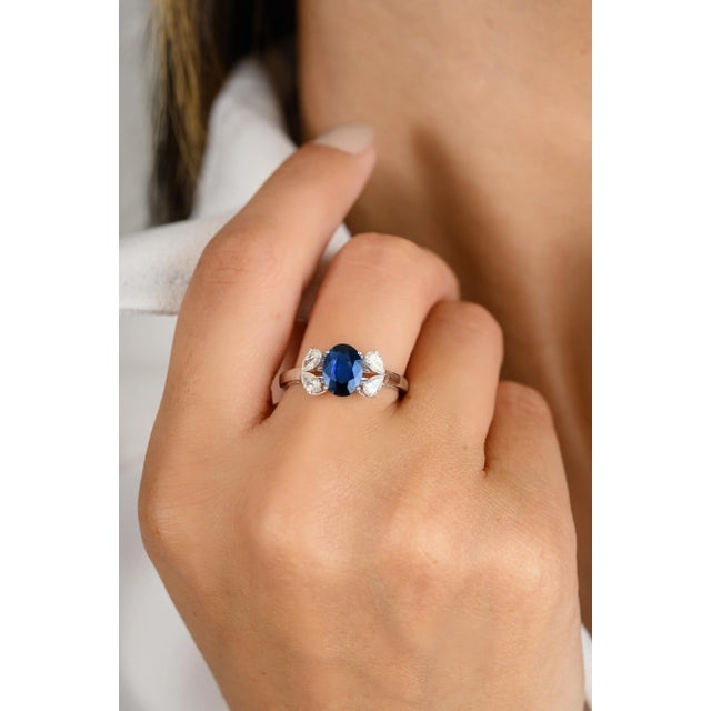 This French modern engagement ring showcases a 1.04 ctw blue sapphire as its center stone, surrounded by four pear-cut...