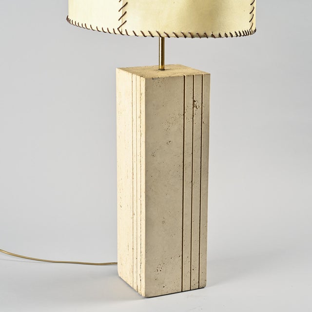Large table lamp composed of a quadrangular travertine base, punctuated by three fine vertical grooves that accentuate the...