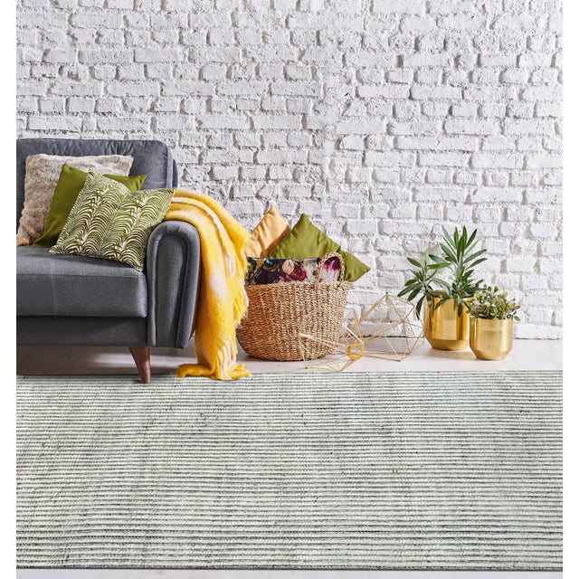 A hand-knotted wool rug, made in India and measuring 5' x 8'. Geometric drawing - repeating motifs held inside strong...