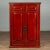 An antique Chinese red cabinet from the early 20th century, with two doors, hidden drawers, carved panels and distressed...
