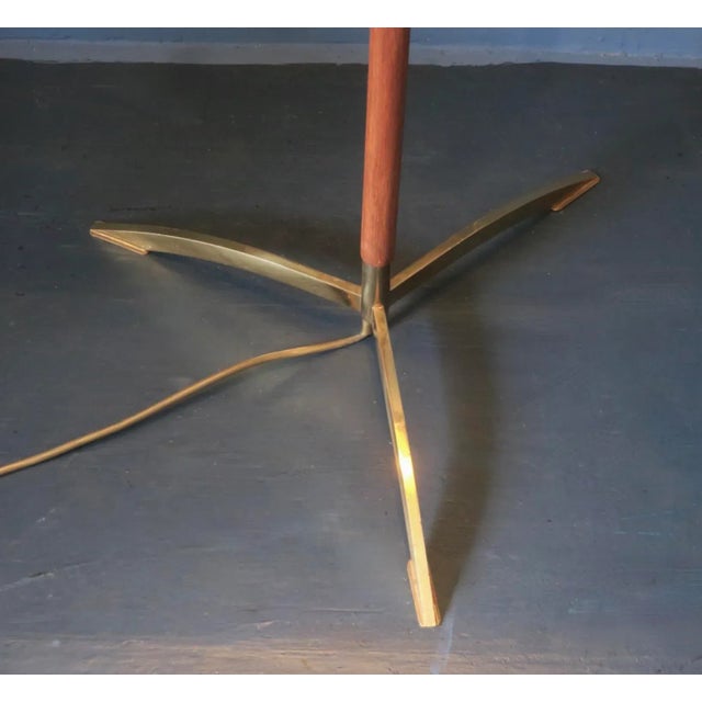 Danish floor lamp in teak on a brass tripod foot, Denmark 1960s. Fine and elegant design. The black shade with copper-...