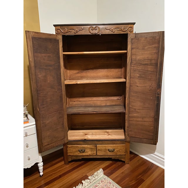 Tall and beautiful vintage wood armoire. Ample storage with 4 shelves, two bottom drawers and metal hooks flanking each...