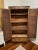Tall and beautiful vintage wood armoire. Ample storage with 4 shelves, two bottom drawers and metal hooks flanking each...