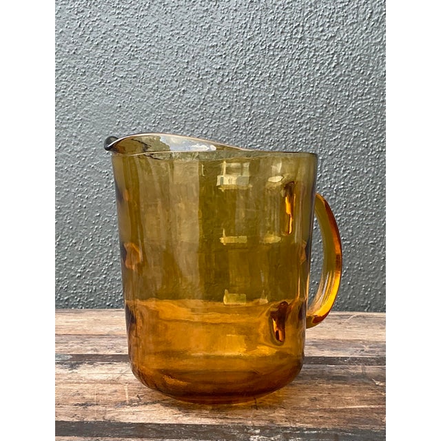 Add a touch of Mid-Century warmth to your glassware collection with this striking amber glass pitcher. Defined by its...