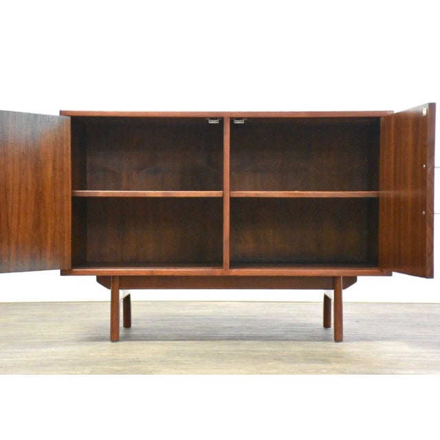 A mid century modern walnut two door credenza cabinet with aluminum pulls designed by Jens Risom. Finished back....