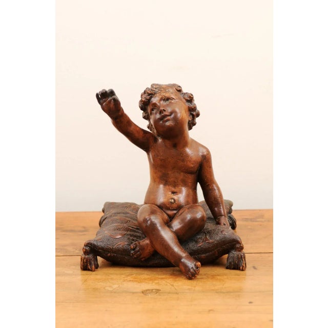 A French Baroque style walnut putto from the late 18th century, sitting on a pillow. Created in France during the last...