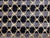 Hand-knotted Nepal wool rug featuring an all-over geometric lattice pattern set on a dark ground with subtle tonal...