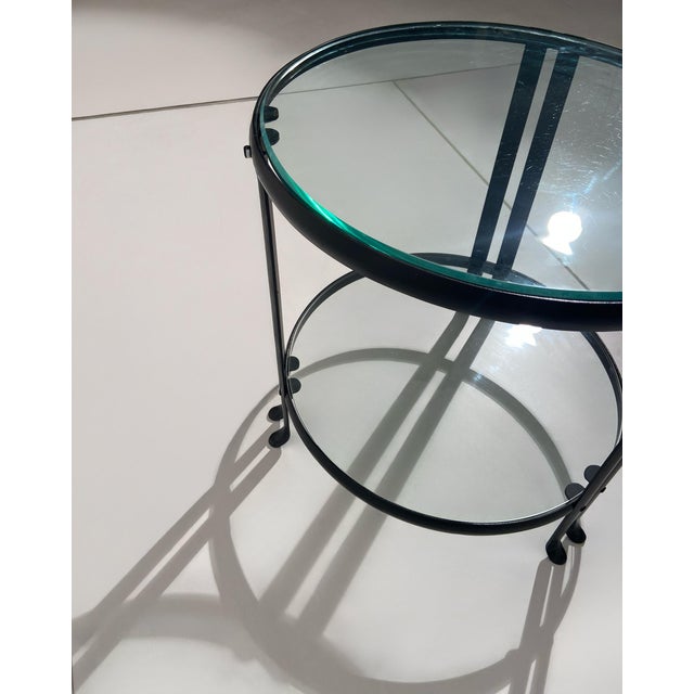 A circular coffee table with a simple and refined design, featuring a wrought iron frame and two round clear glass tops....