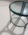 A circular coffee table with a simple and refined design, featuring a wrought iron frame and two round clear glass tops....