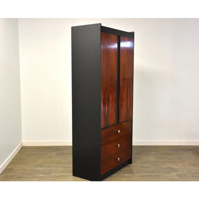 A mid century modern rosewood and black lacquered armoire dresser with chrome accents in the style of Harvey Probber and...