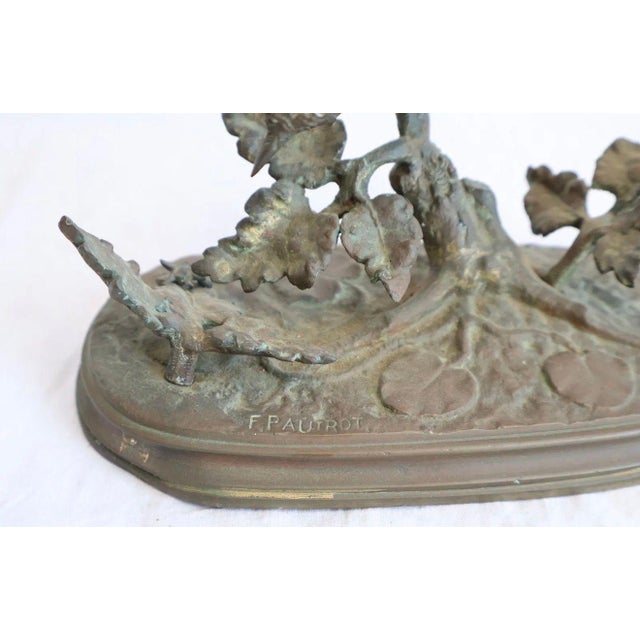 A bronze of a wild bird with wings spread, captured in the moment of alighting on an oak branch — the head turned...