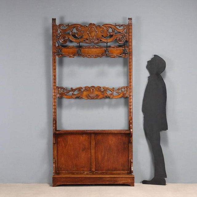 Wall-mounted coat rack in walnut-stained beech. The openwork bands feature floral, leafy, scroll, and curlicues, with a...