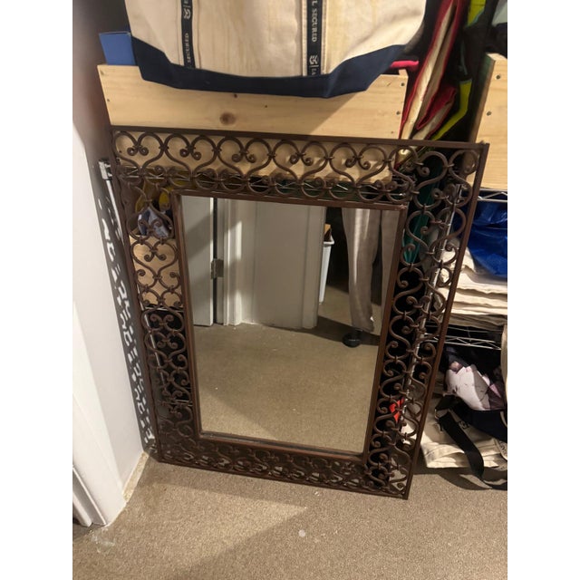 Decorative wrought iron wall mirror featuring an elegant scrolling motif and bronze finish. The intricate openwork frame...