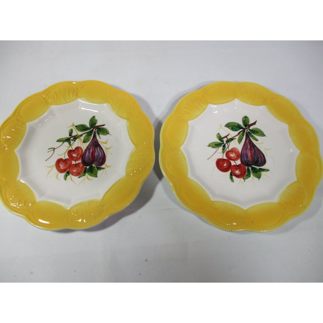 Set of 8 vintage hand painted plates with centers of four different fruit designs. They have a scalloped edge and a yellow...