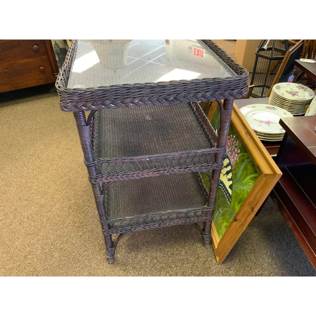Early 20th century wicker tier table. Two shelves. Has a plexi top. Branded with a makers mark that is illegible.