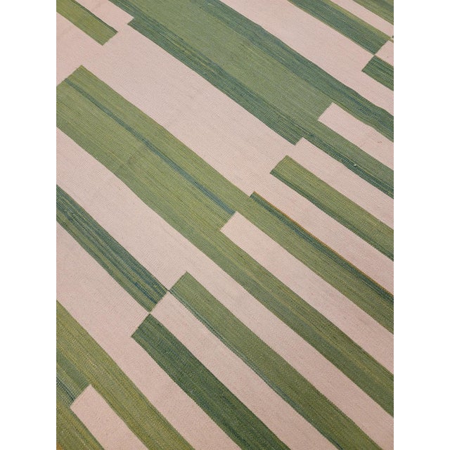 This Modern Green Kilim Flaweave Wool Rug is made of wool and features a contemporary geometric pattern. Its stylish beige...