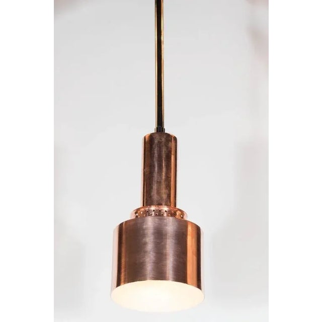 Mid-Century Modernist copper pendant featuring a clean, industrial design. Polished copper with a perforated band lend to...