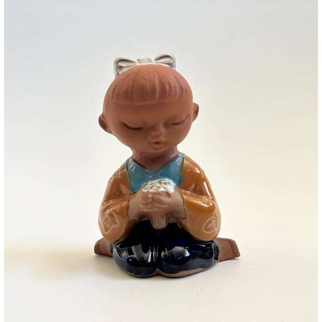 A vintage mid century pottery girl. Lovely detailing with a carved floral design to the girl's jacket. Unglazed natural...