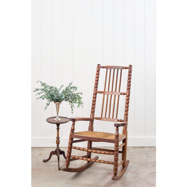 This antique English bobbin rocking chair features turned wood detailing throughout the frame with bobbin-style turned...