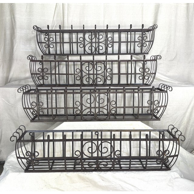 A beautifully matched set of four hand wrought iron window boxes featuring graceful scrollwork and architectural presence....