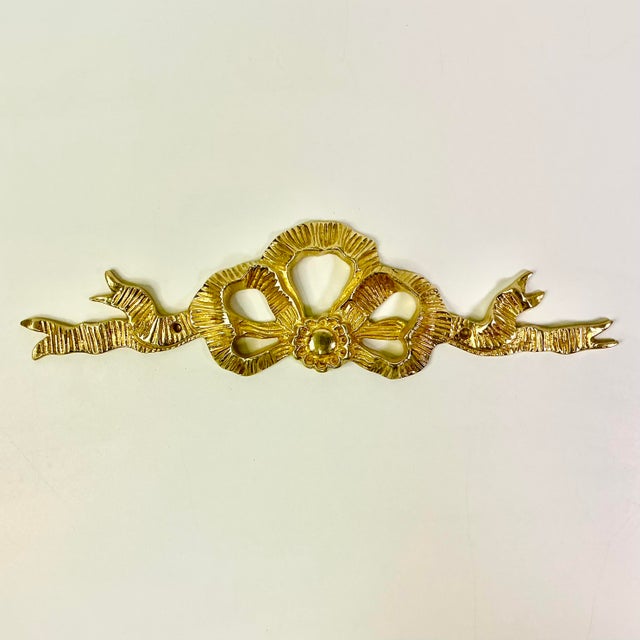 This is a lovely Mid-Century Brass Ribbon and Bow Wall Decorative Pediment. It has Chippendale Hollywood Regency style and...