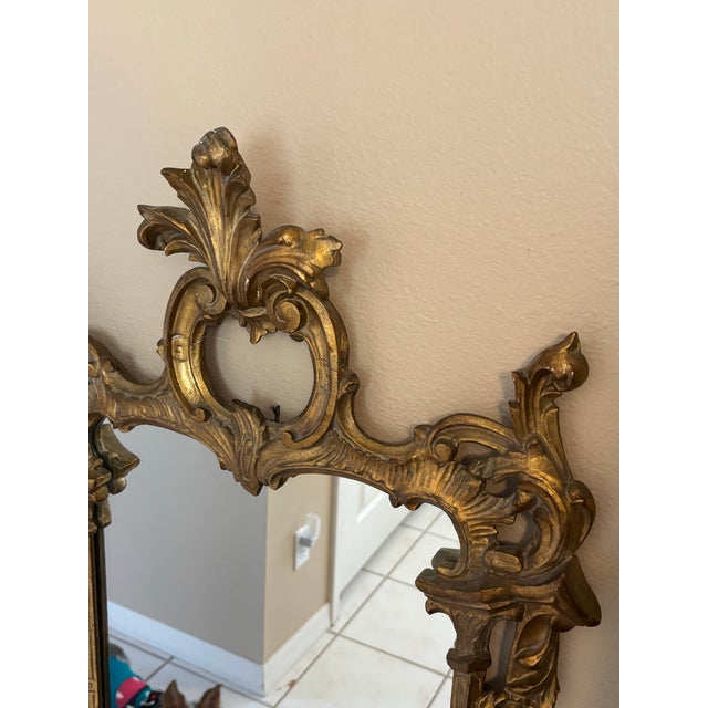 A striking late 19th-century Rococo Revival wall mirror featuring an exceptionally ornate, sculptural frame with an aged...
