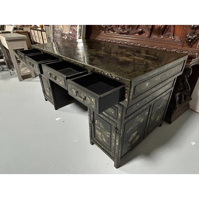 Asian black lacquer writing desk featuring extensive hand-decorated gilt ornamentation throughout. The rectangular top is...