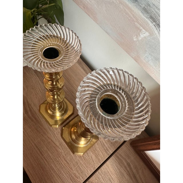 An elegant pair of vintage solid brass candlesticks featuring sculptural turned stems, architectural octagonal bases, and...