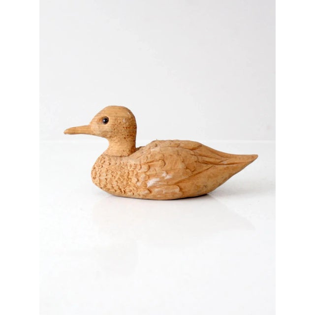 This vintage wooden duck features rustic hand-carved details, a natural unpainted finish, and glass eyes that add a subtle...