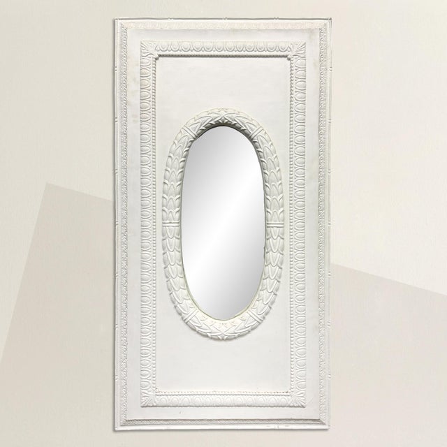 A late 20th-century plaster mirror, rectangular in form, but with a softened center that changes the tone entirely. The...