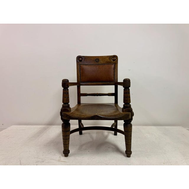 An Arts and Crafts oak armchair dating from the early 20th century, constructed in solid oak with strong architectural...