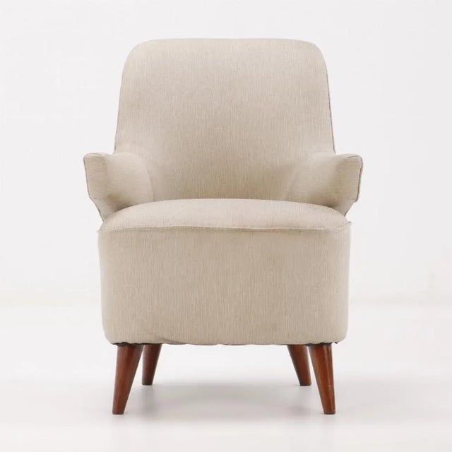 Pair of upholstered lounge chairs circa 1950 having floating arms and new fabric resting on wood feet.