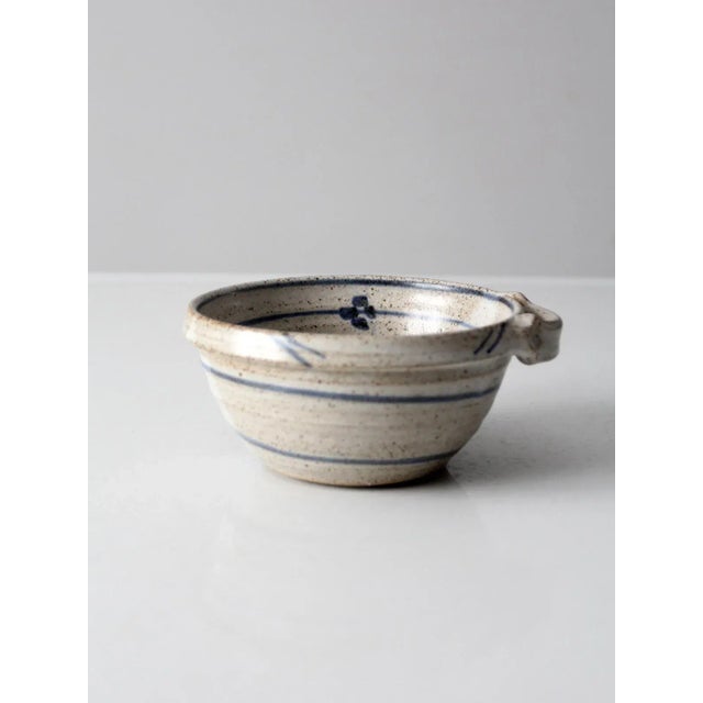 This is a vintage studio pottery bowl. Signed by the artist, Wells, the handmade bowl features a blue stripe and floral...