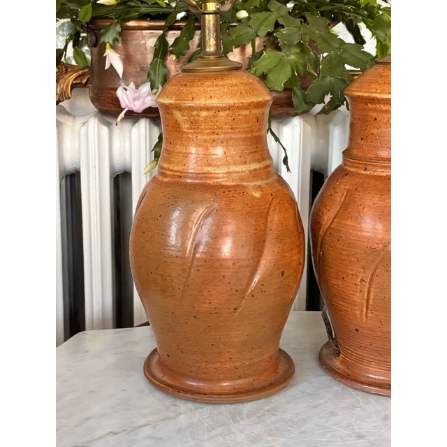A pair of 1970s hand thrown studio pottery table lamps, signed Joe. Topped with brass fittings. Most items found at Pub &...