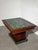 Elegant Art Deco dining table featuring a striking green marble top framed by rich walnut-toned wood. The table stands on...