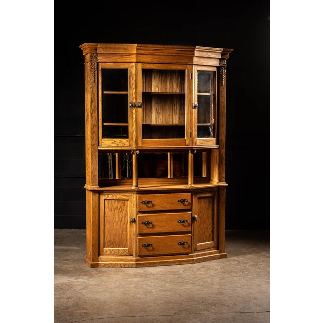 Large-scale oak hutch constructed in three distinct sections, combining display cabinetry, a central serving surface, and...