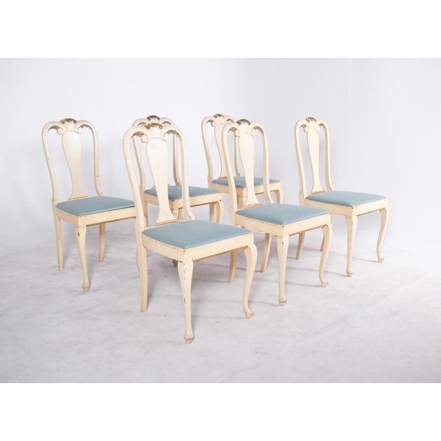 Six wooden chairs painted white. This set of six chairs displays a classic, romantic style influenced by French design....
