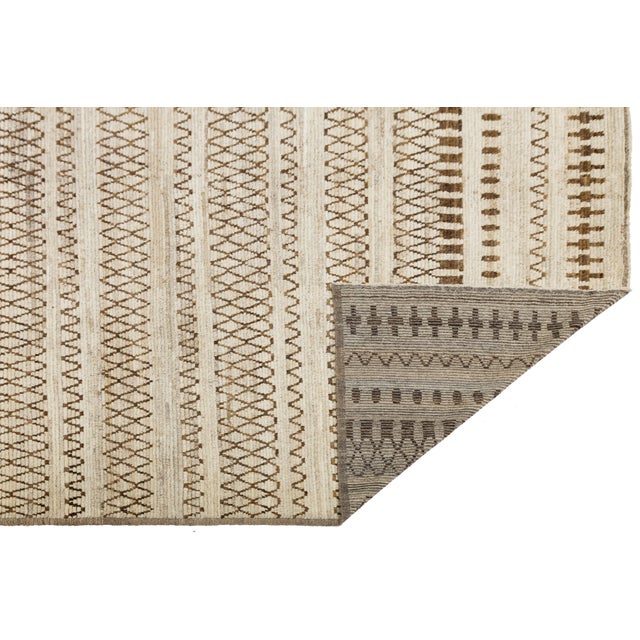 Handwoven in soft wool, this modern Moroccan-style rug features a rhythmic pattern of tribal-inspired geometric motifs in...