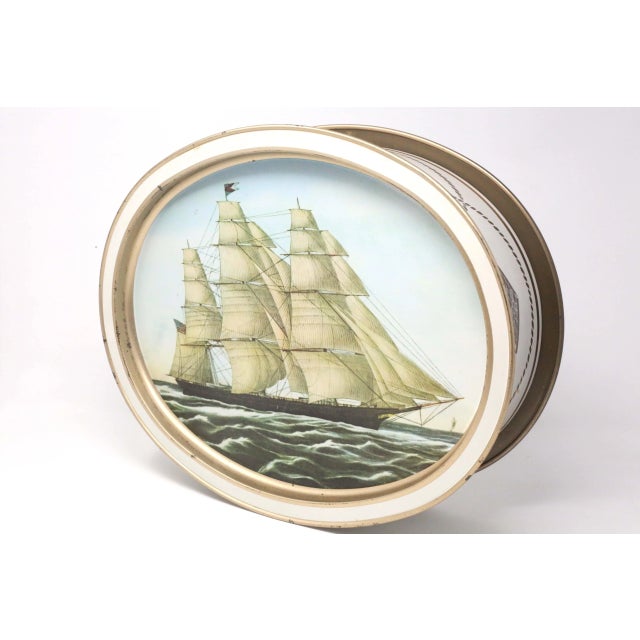 LARGE over 14 inches: A vintage, metal box with an oval shape, decorated with nautical designs and reproduction prints of...