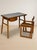 A distinctive mid-century writing desk with a compact rectangular top, slender tapered legs, and an integrated drawer...
